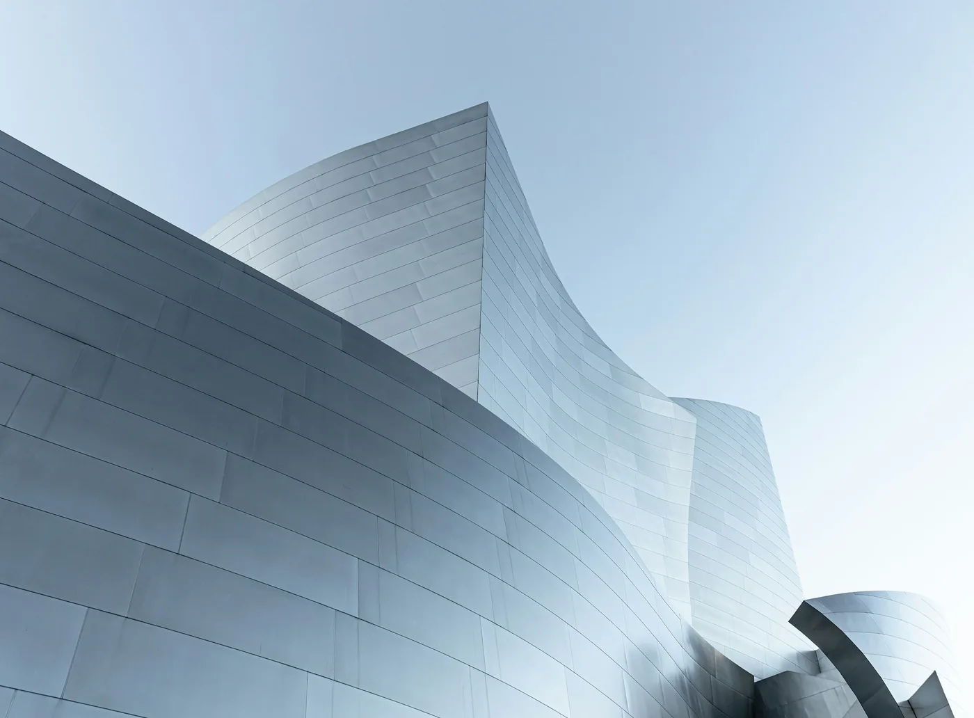 Curved steel facade against a pale sky