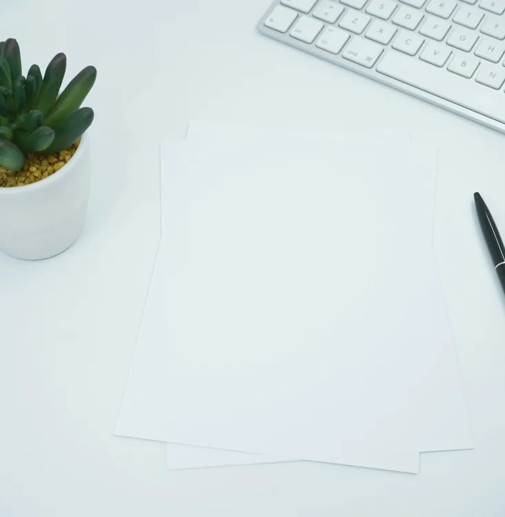 Minimal white desk with keyboard and pen